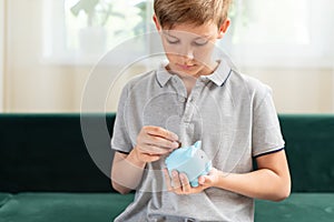 Kid teen boy saving money putting coins in a piggy bank. Learning financial responsibility and projecting savings. The