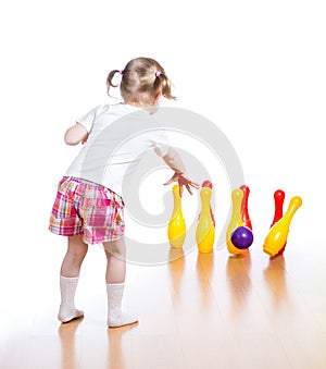 Kid throwing ball to knock down toy pins
