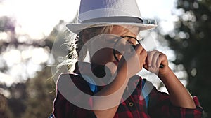 Kid tourist examines flower with a magnifying glass in the park. boyscout travel tourism adventure concept. little kid