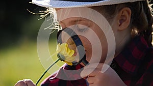 kid tourist examines flower with a magnifying glass in the park. travel tourism adventure concept. little boyscout kid