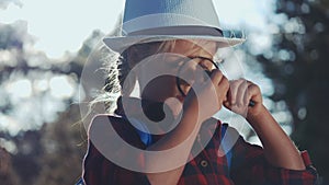 kid tourist examines flower with a magnifying glass in the park. travel tourism boyscout adventure concept. little kid