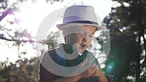 Kid tourist examines pine cone with a magnifying glass in park. travel tourism adventure concept. little kid boyscout