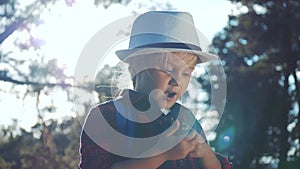 kid tourist examines pine cone with a magnifying glass in park. travel tourism adventure concept. little kid boyscout