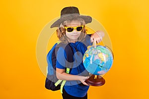 Kid tourists with backpacks and camera hold world globe isolated on yellow studio background. Child boy with backpacks