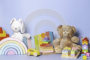 Kid toys collection isolated on blue background. Teddy bear, white bunny, wooden, plastic and fluffy educational baby