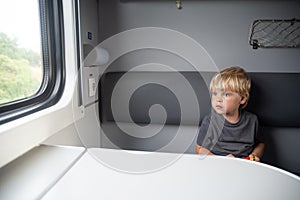 Kid in a train compartment looks out the window. The passenger in the express