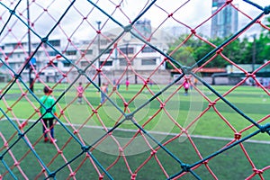 Kid is training soccer football blur background behind the net