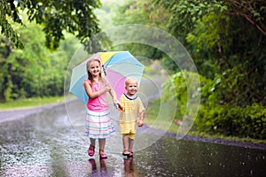 Kid with umbrella playing in summer rain.