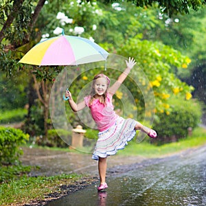 Kid with umbrella playing in summer rain.