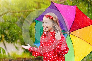 Kid with umbrella playing in summer rain
