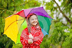 Kid with umbrella playing in summer rain