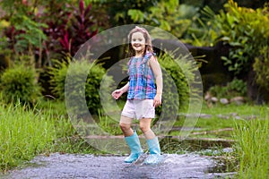 Kid with umbrella playing in summer rain