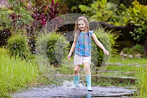 Kid with umbrella playing in summer rain