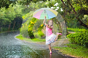 Kid with umbrella playing in summer rain.