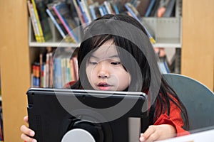 Kid using digital tablet in library