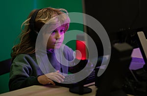 Kid using pc at night. Child with computer in a dark room. A little boy child uses a desktop at night, a child with