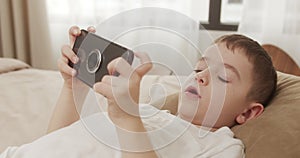 Kid using phone for gaming. Handsome child boy 6 years old playing mobile game on smartphone at home. Adorable kid boy