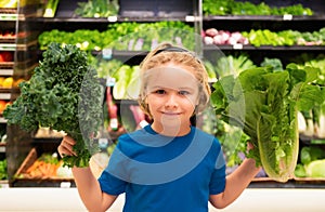 Kid with vegetables at grocery store. Healthy food for kids. Portrait of smiling little child with shopping bag at