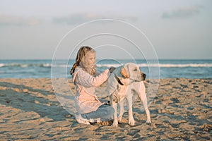 kid walking with labrador dog on beach