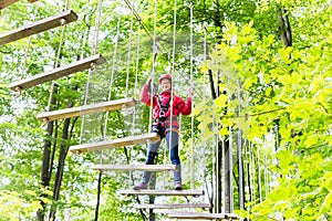 Kid walking on rope bridge in climbing course