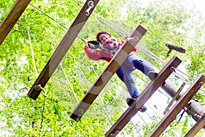 Kid walking on rope bridge in climbing course