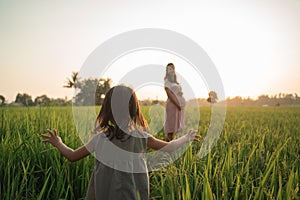 Kid walking toward her mother in the rice field