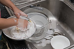 Kid washing dishware in the kitchen sink