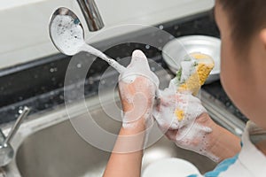 Kid washing dishware in the kitchen sink