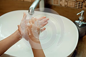 kid washing hands with water and soap in bathroom. Hands hygiene and virus infections prevention.