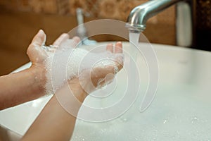 kid washing hands with water and soap in bathroom. Hands hygiene and virus infections prevention. Morning routine.