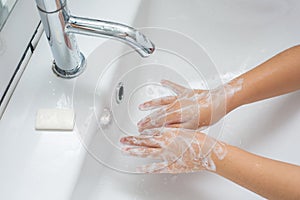 Kid washing hands in a white basin with a bar of white soap