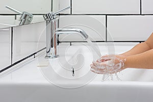 Kid washing hands in a white basin with a bar of white soap