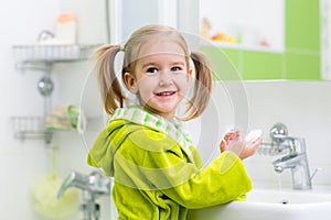 Kid washing her face and hands in bathroom