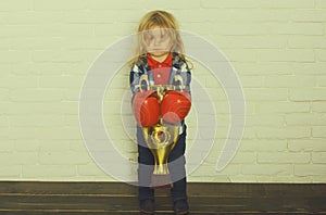 Kid wearing boxing glove, boy boxer winning golden champion cup