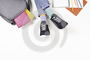 Kid wearing different pair of socks. Child foots in mismatched socks and colorful sneakers, backpack with books and