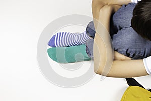 Kid wearing different pair of socks. Child foots in mismatched socks sitting on white background. Odd Socks day, Anti