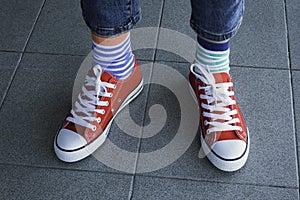 Kid wearing different pair of socks. Child legs in mismatched socks on gray background. Odd Socks day, Anti-Bullying