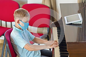 Kid wearing a mask and playing the piano at lesson and event. Kids back to school concept
