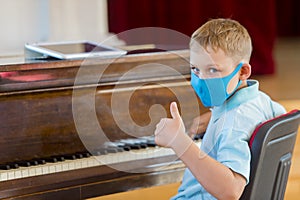 Kid wearing a mask and playing the piano at lesson and event. Kids back to school concept