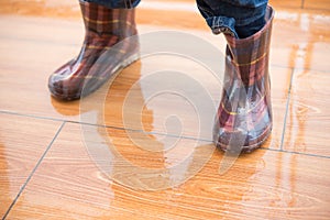 Kid wearing waterproof gumboots standing on wet floor