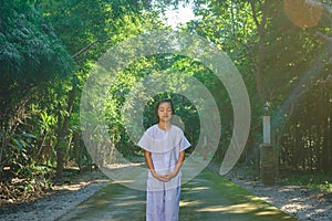 Kid on white clothing , practice walking Meditation in forest tr