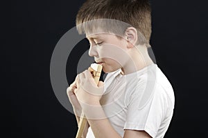 Kid in white playing panflute sideview photo
