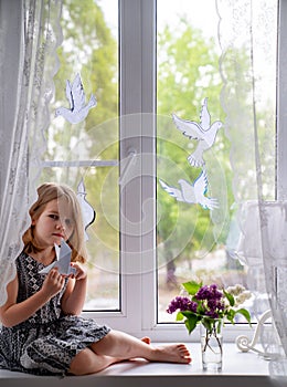 Kid on windowsill with doves symbolizing peace