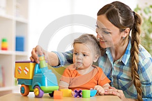 Kid and woman playing with developmental toy in daycare or kindergarten