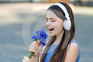 Kiddie song. Happy kid sing song outdoors. Using flowers as microphone. Little child enjoy singing in headphones