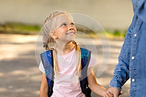 Kidnapping children concept. Good little gullible girl holding hand of unrecognizable man, looking at him and smiling