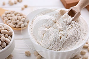 Kidney bean flour and seeds on white wooden table, closeup