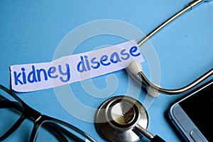 Kidney disease inscription with the view of stethoscope, eyeglasses and smartphone on the blue background.