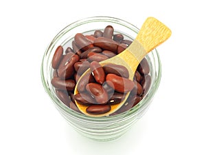 Kidney red beans in wooden spoon over glass cup isolated on white background.