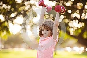 Kids active healthy lifestyle. Sporty child with dumbbell outdoor. Kids sport. Boy exercising in park.